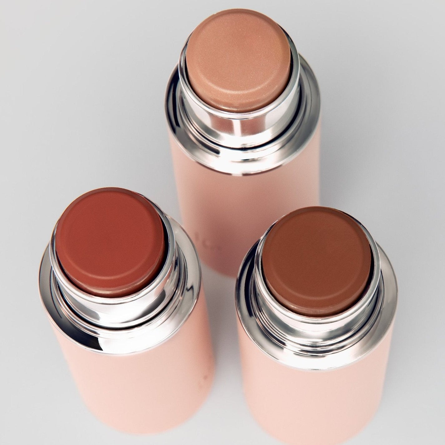 Three cylindrical makeup stick containers with different shades.